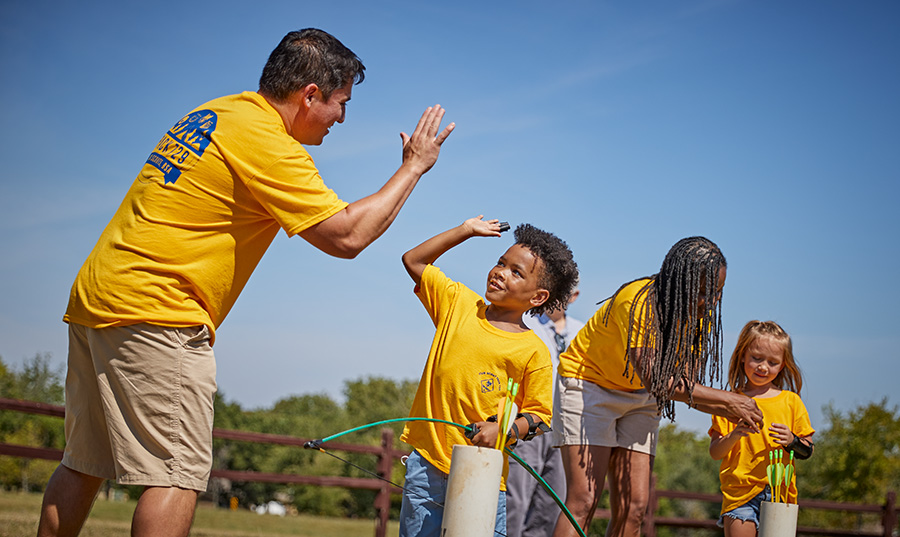 Den leader and cub scout high fiving at archery range
